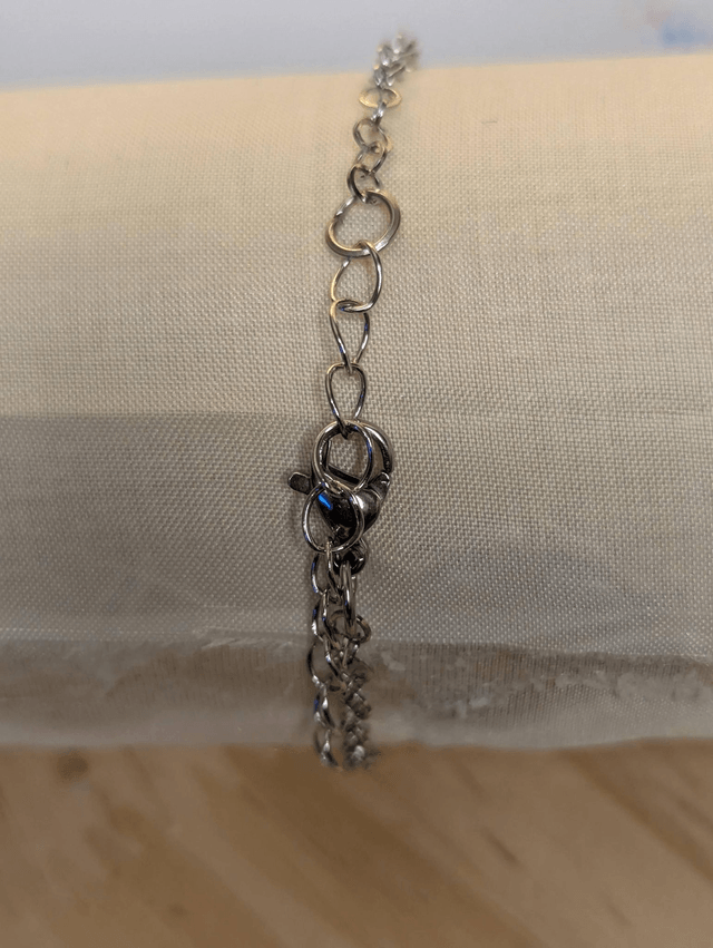 Bracelet avec une chaine en argent, un pendentif en résine noir, avec des fleurs séchés rouge, le fermoir est en argent.