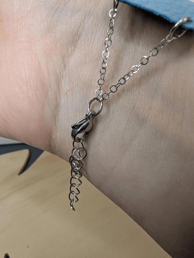Bracelet manchette en cuir bleu, avec du tissus enduit bleu foncé (résistant), une chaine argentée. Le fermoir est de couleur argent.