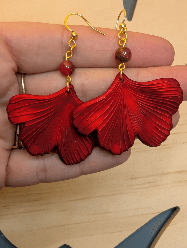 Boucles d'oreilles avec pendentifs en forme de feuilles de couleur rouge métallisé avec des perles de cloisonne rouge et marron.