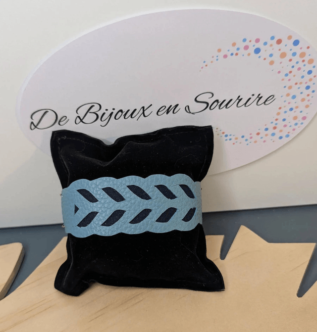 Bracelet manchette en cuir bleu, avec du tissus enduit bleu foncé (résistant), une chaine argentée. Le fermoir est de couleur argent.