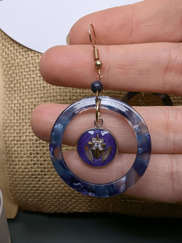 Boucles d'oreilles avec 2 pendentifs, cercle en résine coloré bleu violet, avec des fleurs séchées, des perles naturelle et un fermoir en or. 