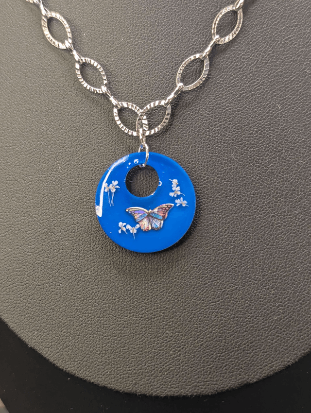 Collier avec une chaine de couleur argent et un pendentif rond  en résine bleu. 