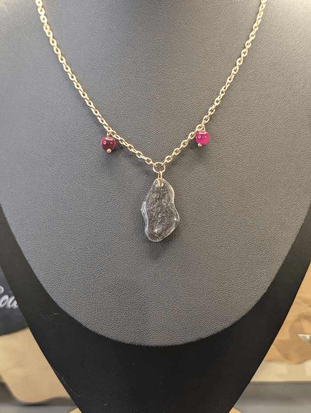 Collier mi long avec une chaine de couleur argent, un pendentif en résine noire et gris pailleté et des perles naturelles rose. 