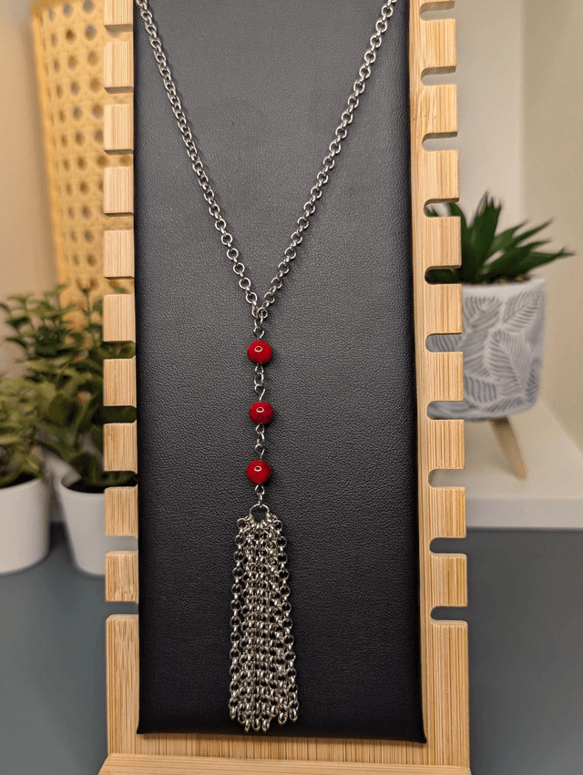Collier long, sautoir, avec une chaine de couleur argent, des perles naturelles de turquoise rouge, et un pompon en chaine argentée. 