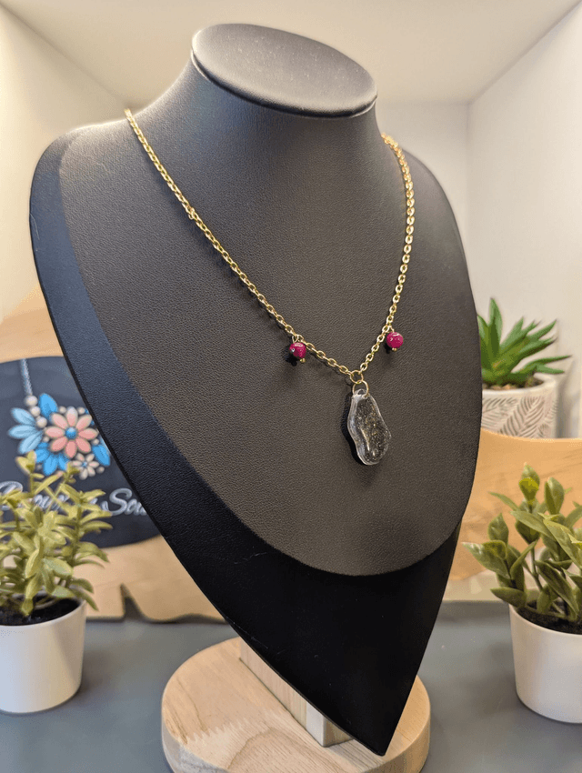 Collier mi long avec une chaine de couleur argent, un pendentif en résine noire et gris pailleté et des perles naturelles rose. 