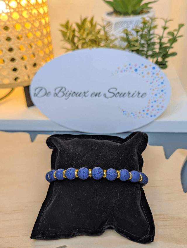 Bracelet en pierre de lave bleu foncé, avec des perles d'espacement doré. Le fermoir et la chaine fermoir sont de couleur or.