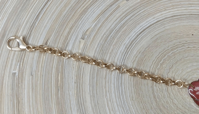 Bracelet ave une chaine de couleur or, pendentif en résine rose et jaune avec des petites fleurs blanches, le fermoir est or.