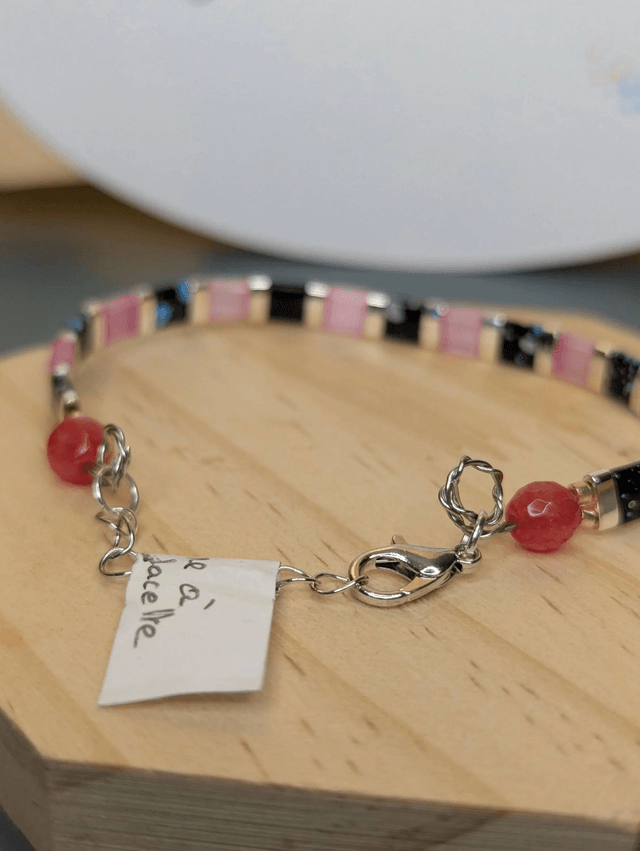Bracelet en perles plate en verre rose et noire, avec des perles en métal argenté. Le fermoir et la chaine fermoir sont en argent.