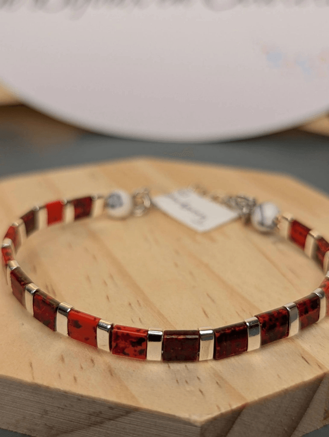 Bracelet en perles plate en verre rouge, perles d'espacement en métal argenté. le fermoir et la chaine fermoir sont en argent. 