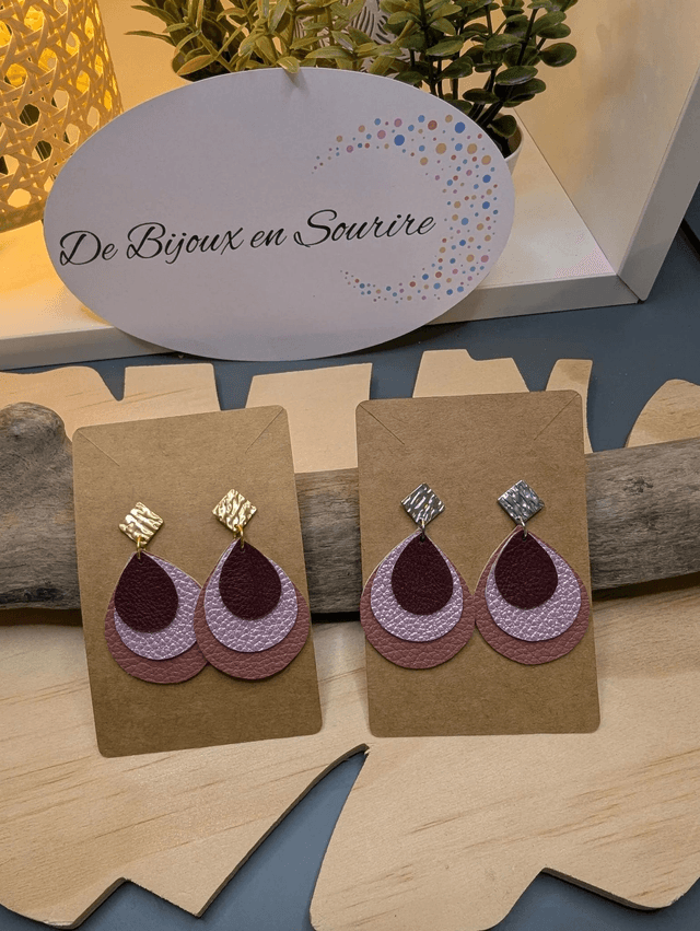 Boucles d'oreilles en cuir en forme de goutte avec un dégradé de rose/violet le derrière est en blanc. Le fermoir en clou carré est de couleur doré.