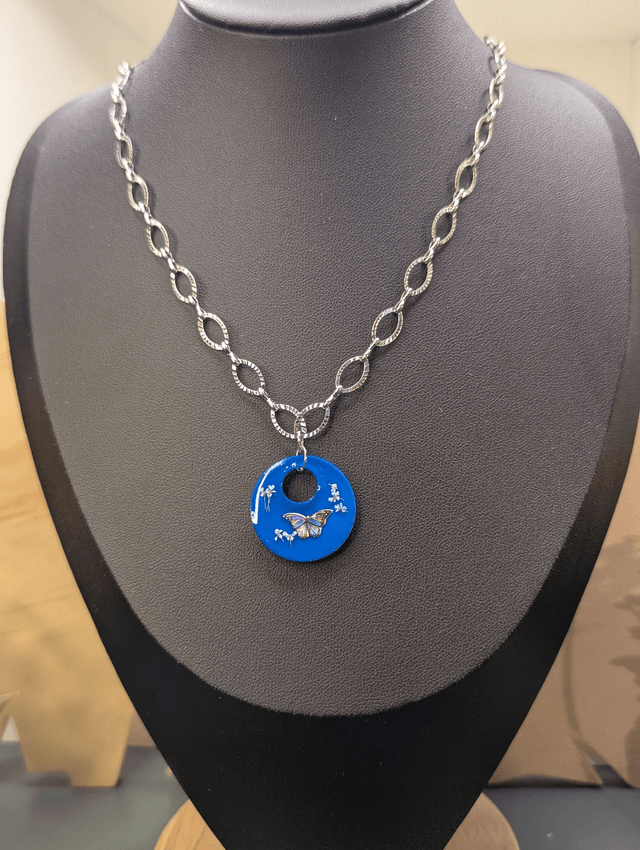 Collier avec une chaine de couleur argent et un pendentif rond  en résine bleu. 