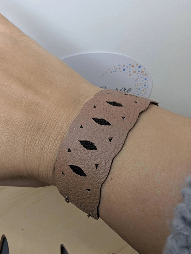 Bracelet manchette en cuir marron clair, avec du tissus enduit noir (résistant), une chaine couleur argent. Le fermoir est  de couleur argent.