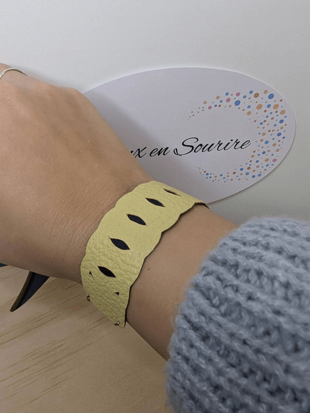 Bracelet manchette en cuir jaune, avec du tissus enduit bleu sombre (résistant), avec une chaine en argent. Le fermoir est de couleur argent.