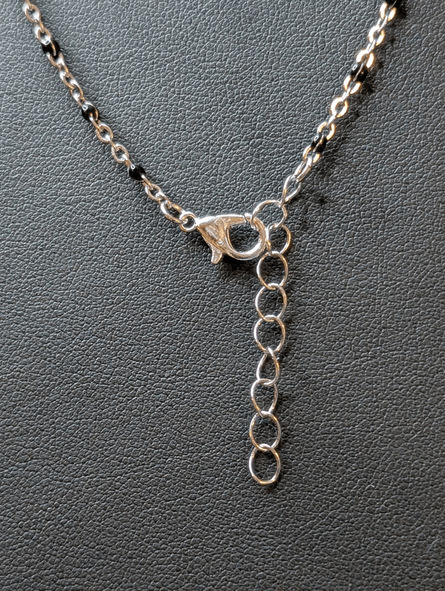 Collier sautoir long avec un pendentif en bois noir et un pendentif en résine rouge, fleurs blanche, chaine en argent. 