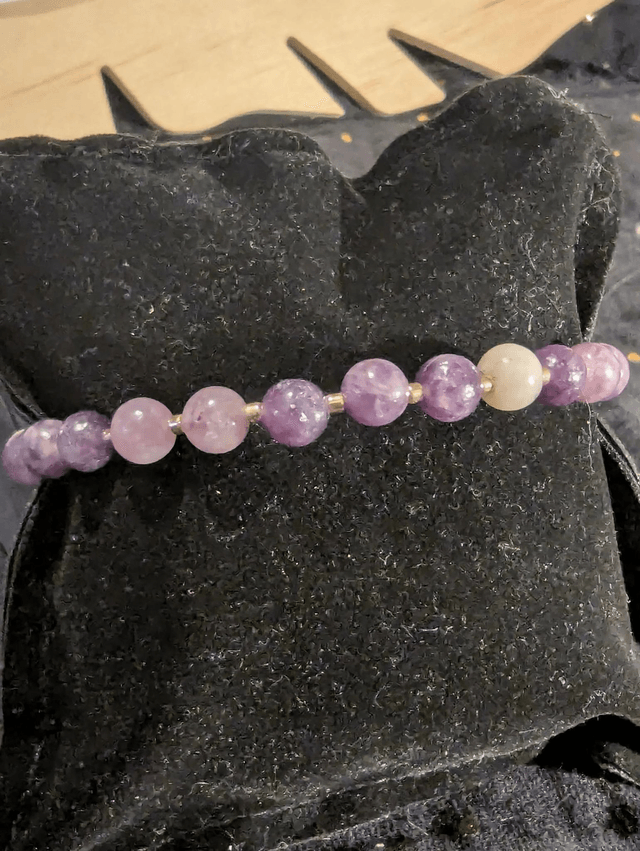 Bracelet en perles de lépidolite violette, et des perles d'espacement violette. Le fermoir et la chaine fermoir sont de couleur or.