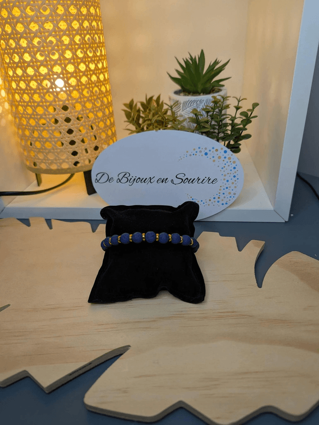 Bracelet en pierre de lave bleu foncé, avec des perles d'espacement doré. Le fermoir et la chaine fermoir sont de couleur or.