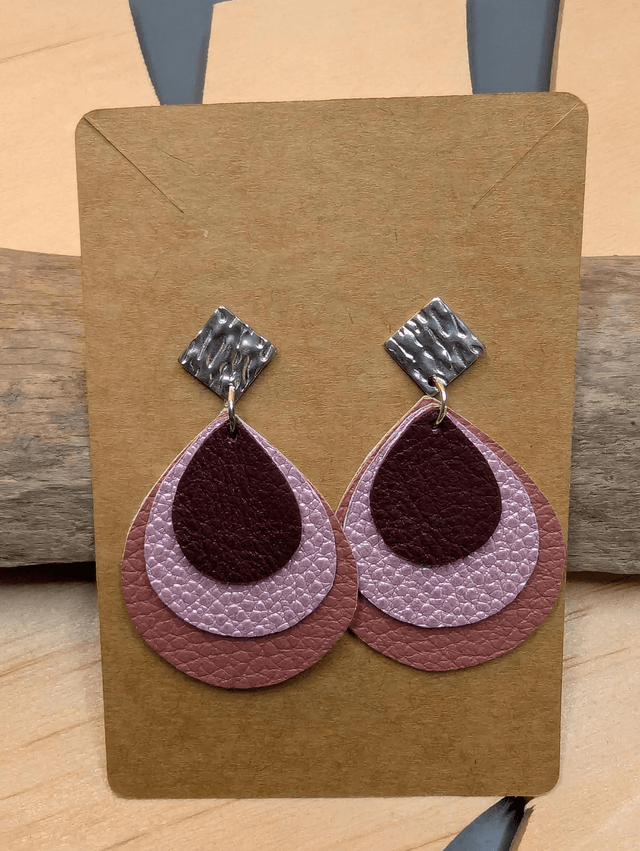 Boucles d'oreilles en cuir en forme de goutte avec un dégradé de rose/violet et le derrière est en blanc. Le fermoir en clou carré est en argent.