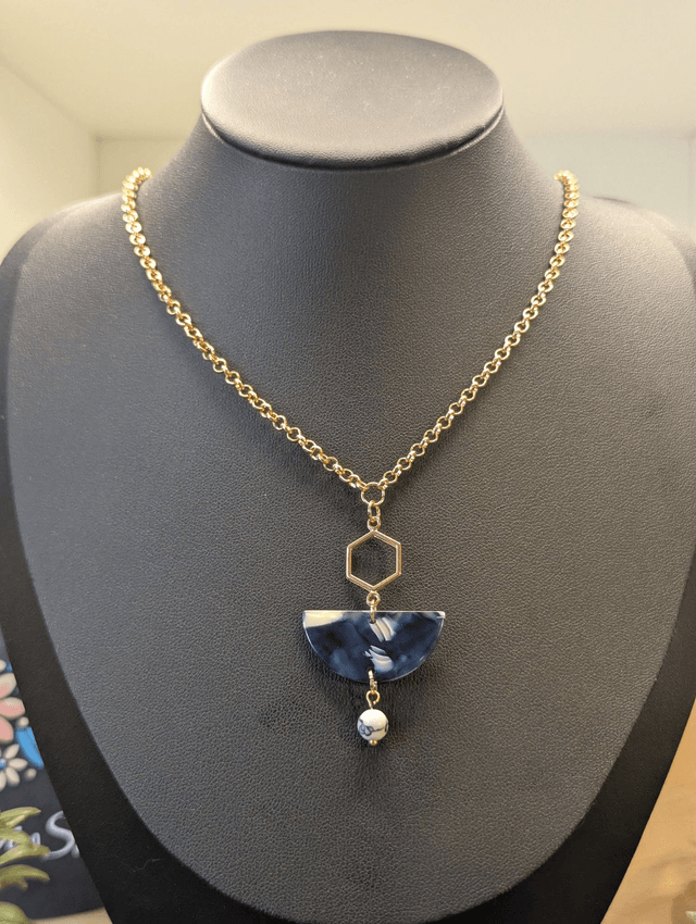 Collier mi long avec une chaine de couleur or et un pendentif en résine bleu et blanc et un pendentif en métal doré.