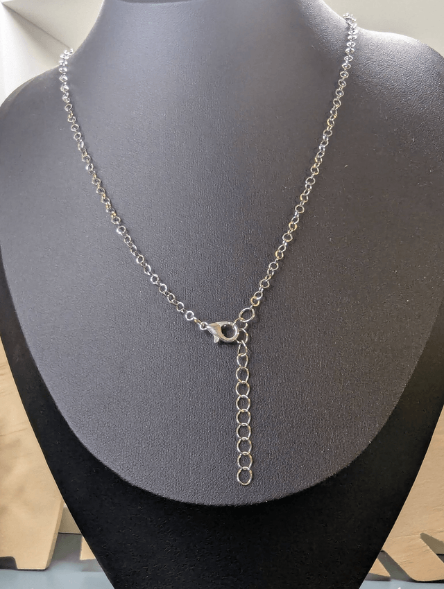 Collier court avec une chaine de couleur argent une perle naturelle et un pendentif en bois noir. 