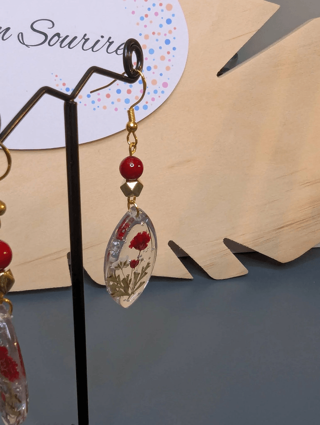 Boucles d'oreilles  avec un pendentif ovale en résine transparente et avec des fleurs séchés, des perle naturelle , le fermoir est en or.