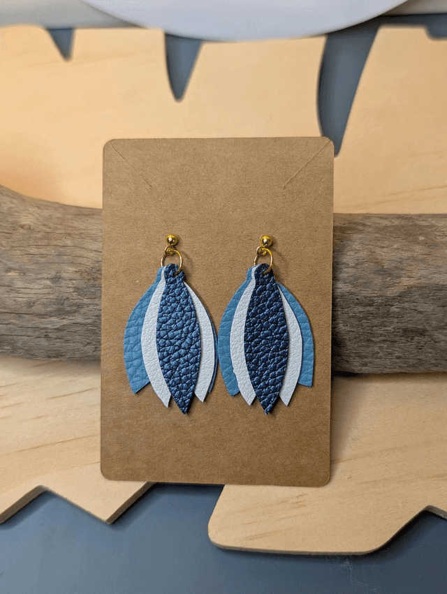 Boucles d&#039;oreilles en cuir en forme de fleur de couleur bleu et blanc le derrière est en tissu enduit, le fermoir clou est en or.