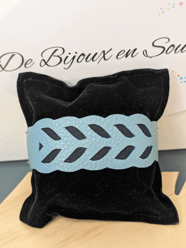 Bracelet manchette en cuir bleu, avec du tissus enduit bleu foncé (résistant), une chaine argentée. Le fermoir est de couleur argent.