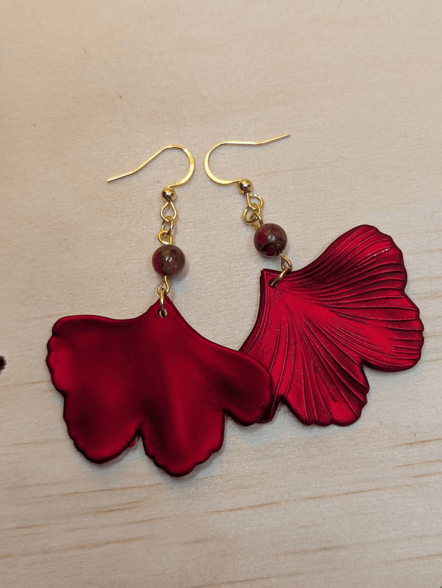 Boucles d&#039;oreilles avec pendentifs en forme de feuilles de couleur rouge métallisé avec des perles de cloisonne rouge et marron.