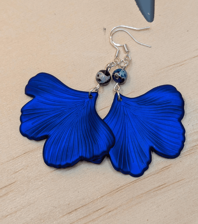 Boucles d&#039;oreilles avec pendentifs en forme de feuilles de couleur bleu métallisé et des perles de jaspe sédiment de mer. 