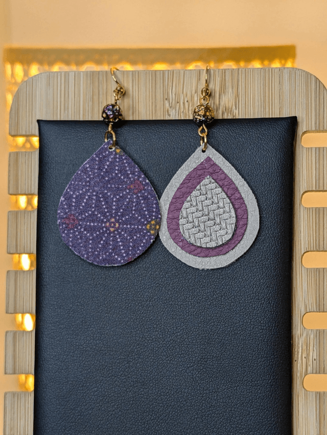 Boucles d&#039;oreilles pendante en similicuir et en tissus enduit violet, gris argenté. avec des perles naturelles le fermoir de la boucle est en or. 