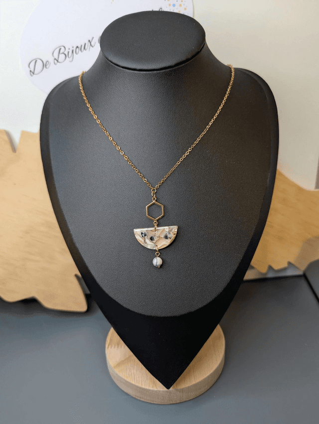 Collier mi long avec une chaine de couleur or et un pendentif en résine rose et noir et un pendentif en métal doré.