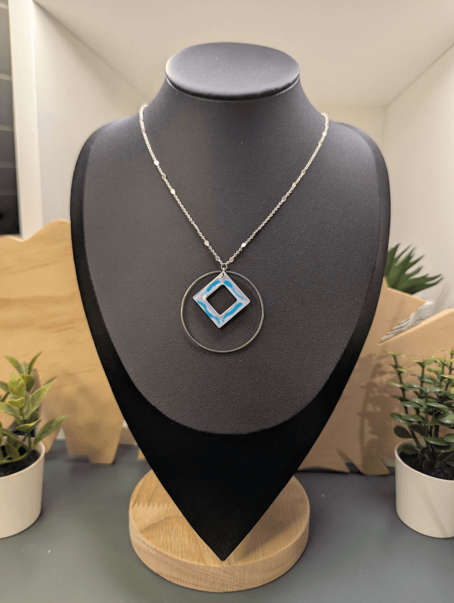 Collier court avec une chaine de couleur argent, un pendentif avec carré en résine et un cercle en métal argenté. 